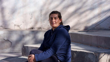 A woman sits on steps and poses for a photo.