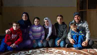 A family in Lebanon sit together in a living room and pose for a photo.