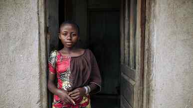 A girl poses for a photo while standing in a doorway in the Democratic Republic of Congo.