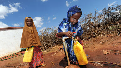 Two girls fill water jugs at an IRC-installed tap in Galkayo, Somalia 