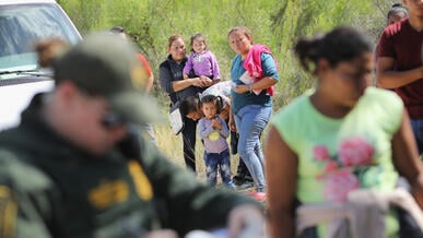 Central American asylum seekers wait as a U.S. Border Patrol agents take groups of them into custody on June 12, 2018 near McAllen, Texas. photo by John Moore/Getty Images