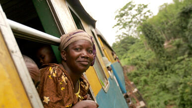 Congolese woman sticking head out of moving railroad car en route to market.