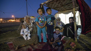 A family made homeless by violence sits outside their makeshift shelter in northern Iraq