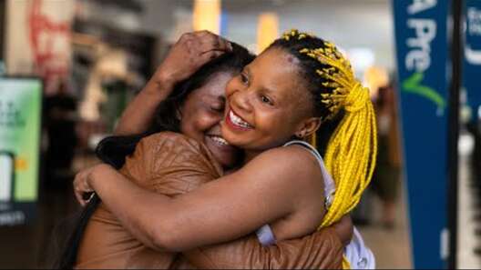 Two sisters embrace warmly and smile together.