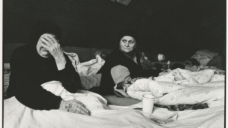 two elderly refugee women lying on matresses in a tent