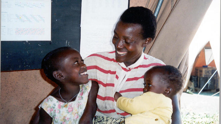 a mother smiles at her two children, one of them still a baby