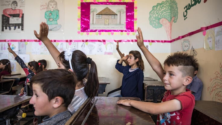 Barn räcker upp sina händer i ett klassrum