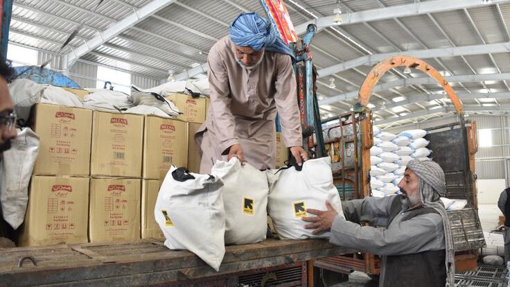 Men work to unload a truck full of food supplies in a warehouse