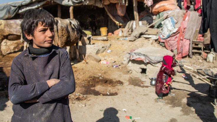 A boy, living in Ghaibi Bala camp in Kabul, Afghanistan, looks on as his mother is interviewed by IRC staff.