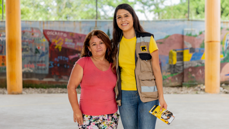 Aracely poses for a picture with an IRC staff member, both stand smiling.