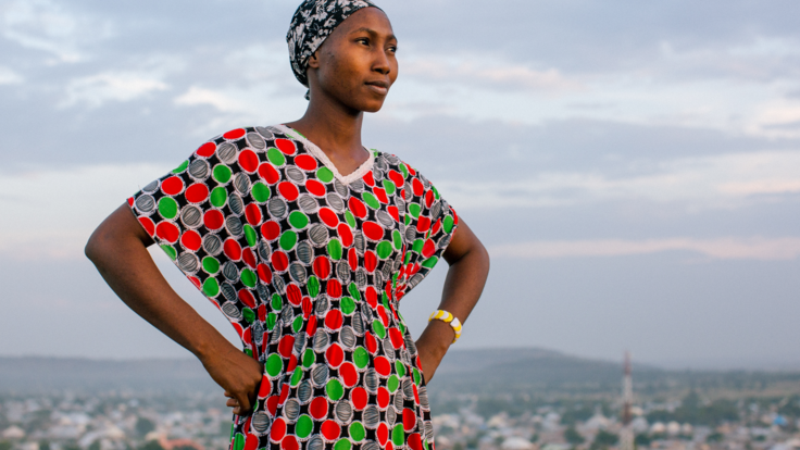 Lydia poses for a portrait on a hill above a city.