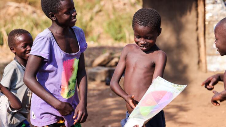 Children point and smile at PlayMatters at Home packets.