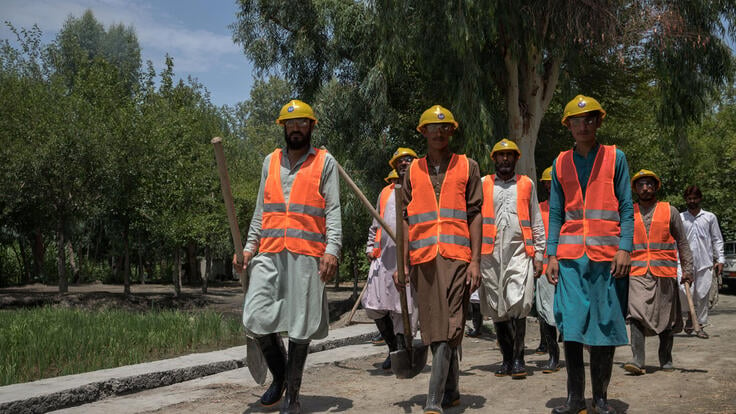 A group of men walk together, all part of a new canal construction in Afghanistan.