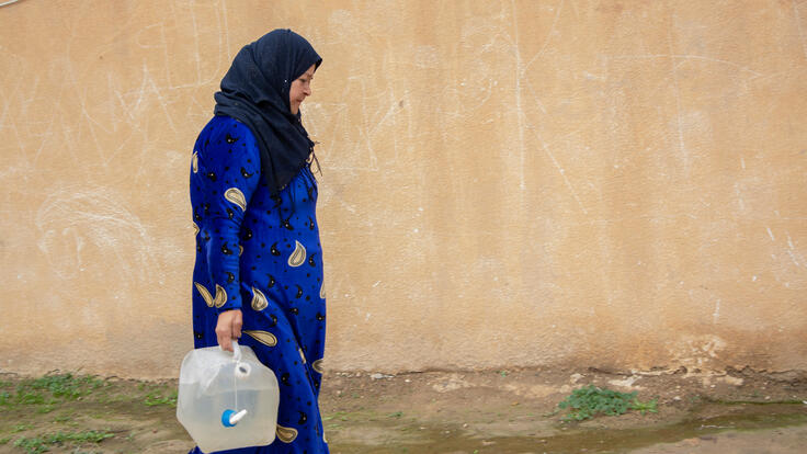 Sayida carries clean water back to the camp where she lives.