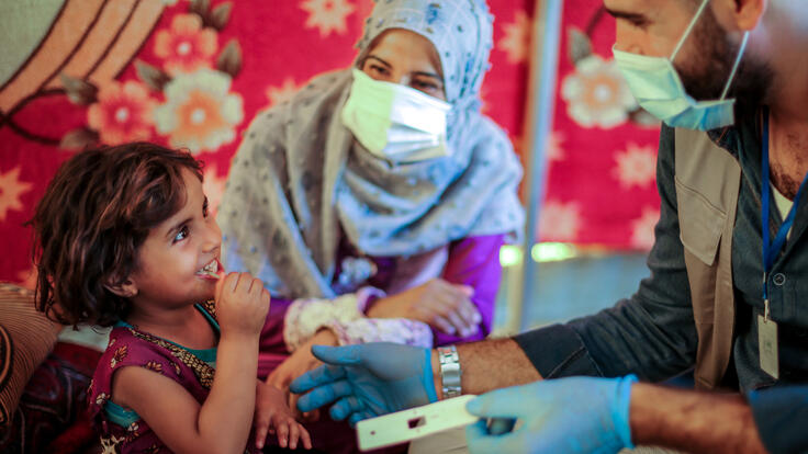 An IRC health team member checks Sarra for malnutrition.