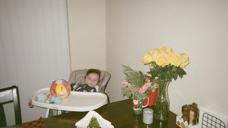Michael is sat in a high chair at kitchen table