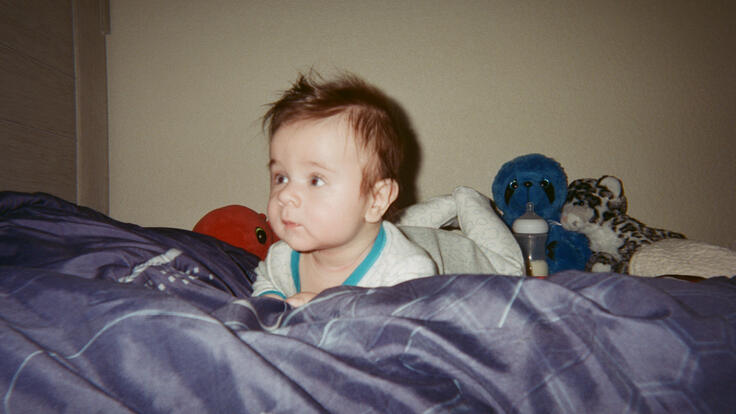 Baby Michael lies on his front on the bed