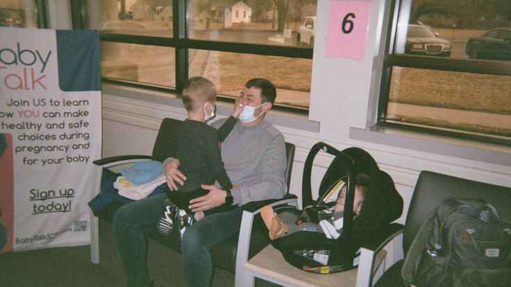 Evgen sits with Oleskii on his lap, in hospital waiting room