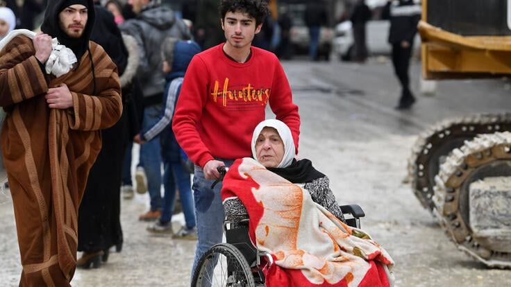 Man pushes elderly women in wheelchair after earthquake hits Syria.