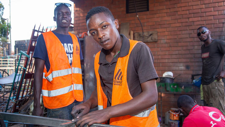 Two men take a break from working at a construction site and pose for a picture.