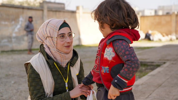 A young boy in northwest Syria receives food items from an IRC emergency response worker.