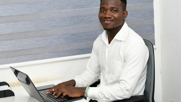 Sebastian turns to the camera for a portrait while working on his computer.