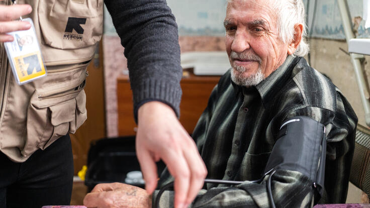 An elderly man has his blood pressure taken by an IRC nurse.