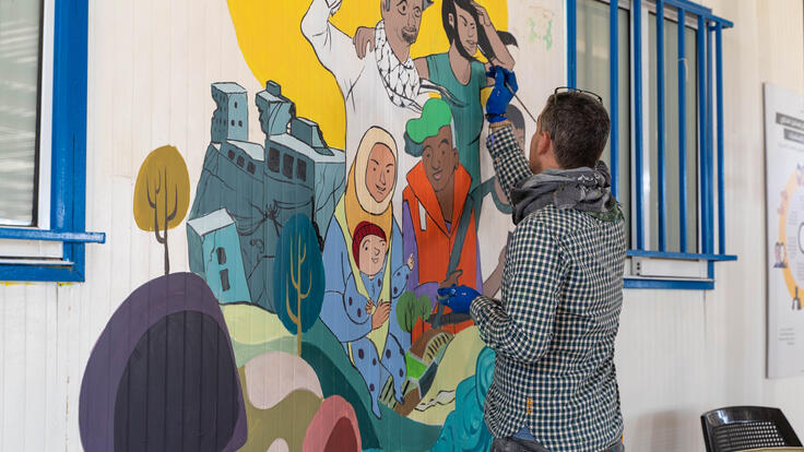 Muhammad, a refugee who fled the conflict in Syria in 2013 and settled in Zaatari camp in Jordan, paints a mural to celebrate World Refugee Day.