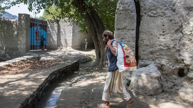 A man walks with a sack over his back, filled with pickles to sell at the bazar.
