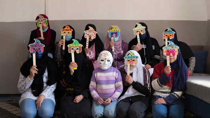 A group of young Syrian refugee girls wearing masks they made during a drawing activity.
