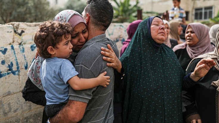 Palästinenser*innen  umarmend und trauernd abgebildet.