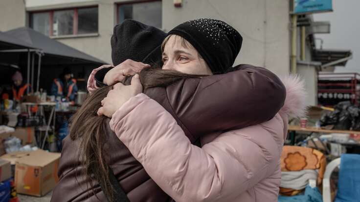 En mamma och hennes vuxna dotter kramas vid gränsövergången vid den Ukrainsk-Polska gränsen. 