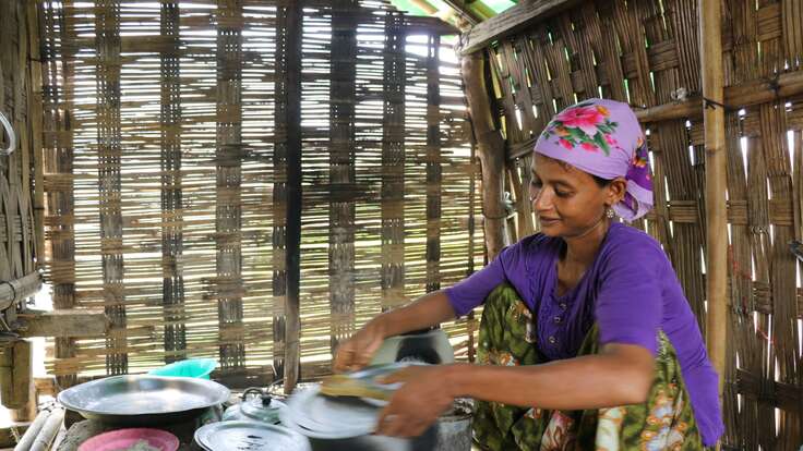 A woman cleans dishes after cooking in her home in Myanmar.