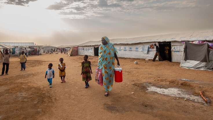 Fairuz stands outside the camp with her grandchildren.