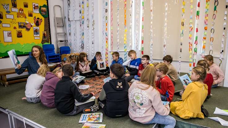 Kinder sitzen im Klassenraum und hören einer Vorlesung zu.