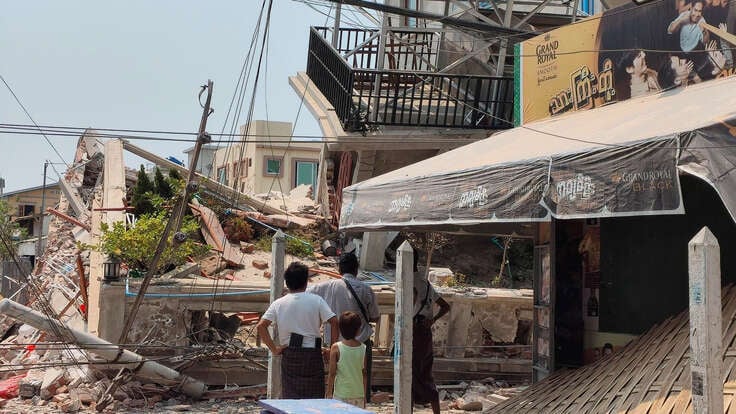 A family examines the severe destruction of their neighborhood, destroyed by the earthquake in Myanmar.