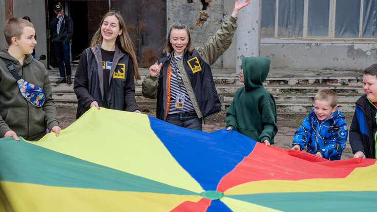 Barn i en by i Charkiv-regionen, Ukraina, deltar i en psykosocial stödsession ledd av en medarbetare från RESCUE.