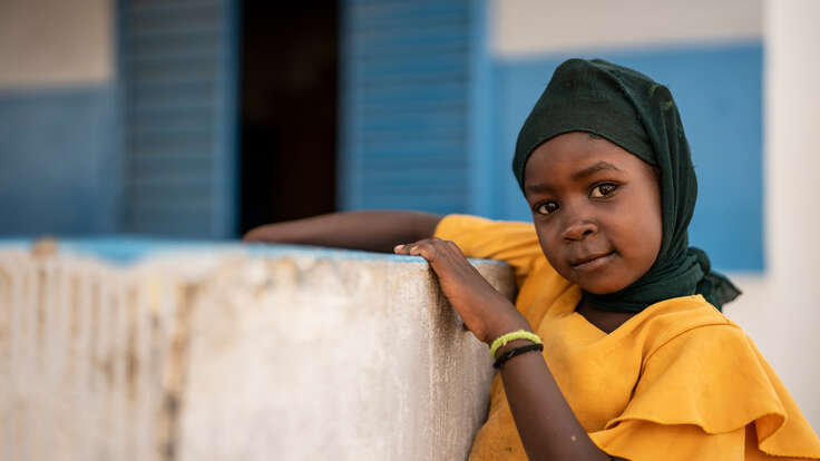 En flicka lutar sig mot en betongmur. 