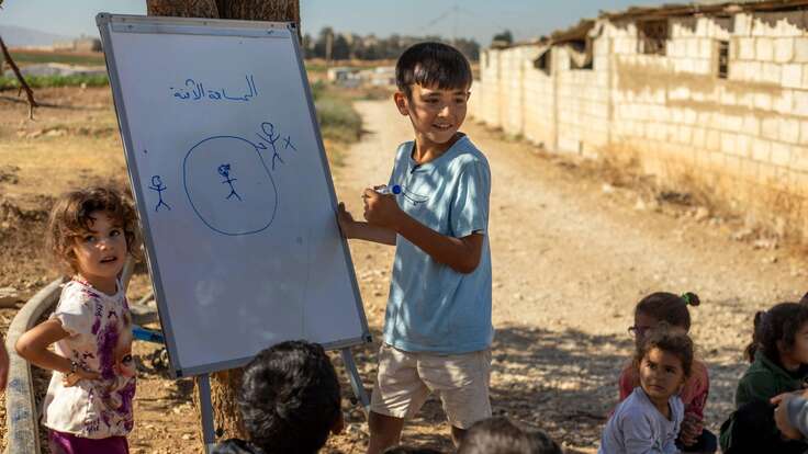 Osama erklärt anderen Kindern an einem Whiteboard, was persönlicher Raum bedeutet.