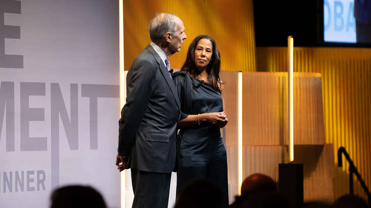 Two people stand together on the stage of the IRC's Global Rescue Dinner.