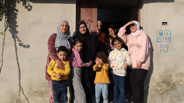 Al-Qusayr, Homs province, Syria. Bayan, 32, stands with her family at the entrance of their repaired family home after returning from 13 years of displacement in Lebanon.