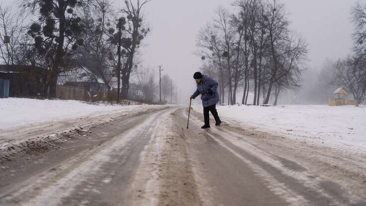 An elderly woman crosses the street in a remote village in the Sumy region.