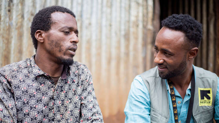 Remedan Jibro (35) und Abdurahman Gidi, IRC-Gesundheits- und Ernährungsbeauftragter, sitzen vor Remedans Zuhause im Geflüchtetenlager für Binnenvertriebene in Deder, Äthiopien.