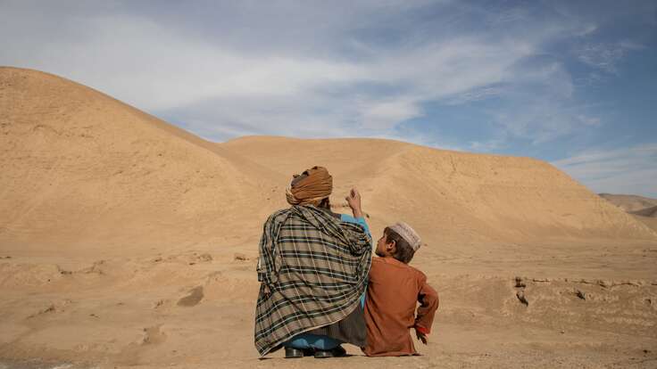 Abdul Haq outside with his oldest son Naqib Ullah as they talk about their village mountains in Afghanistan.