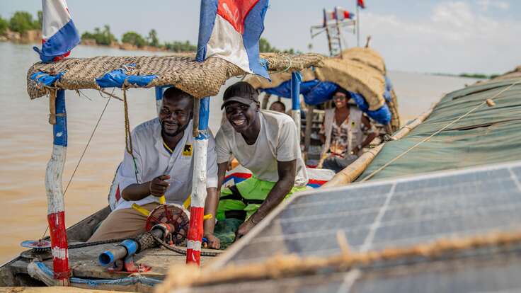 Two men from IRC staff smiling from a boat 