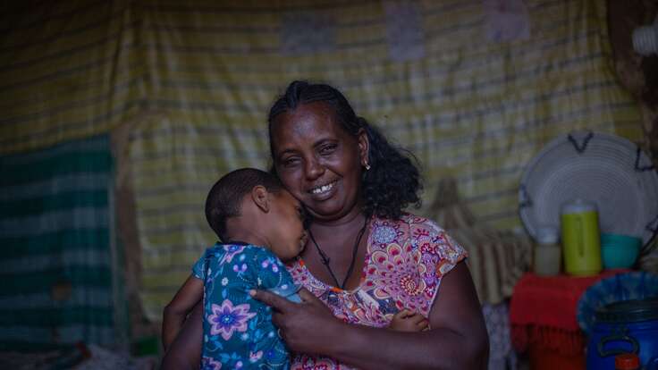 Birhe holds her young child in a shelter after being displaced by war and receiving IRC medical care.