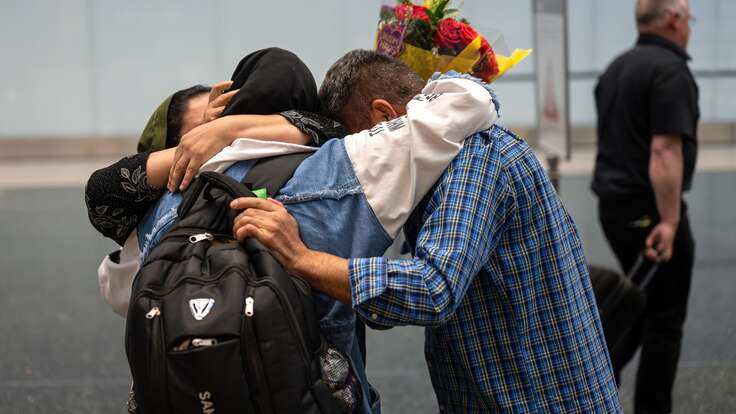 The Hussaini family embraces at a U.S. airport, reunited after fleeing Afghanistan with IRC legal help.