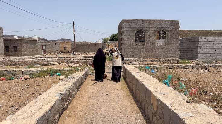 Basma walks with an IRC staff member 