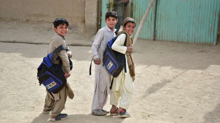 Three boys walk through a school yard in Pakistan.