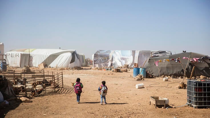 Syrian children walk through rows of tents in a refugee camp in Jordan